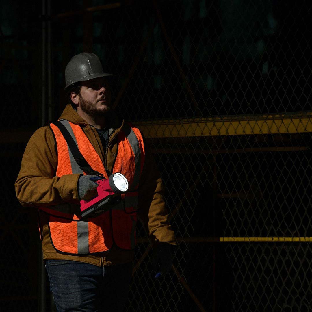 A construction worker holds the Raptor FLood at nightshining it to light his path